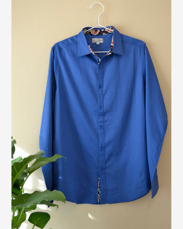 camisa de hombre azul con detalles estampados y en algodón orgánico colgada en la pared
