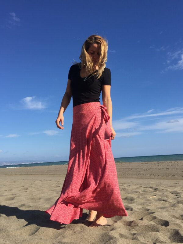 mujer con una falda larga estampada color pink en la playa