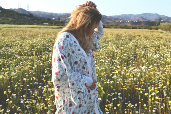 woman in a field of daisies touching her hair