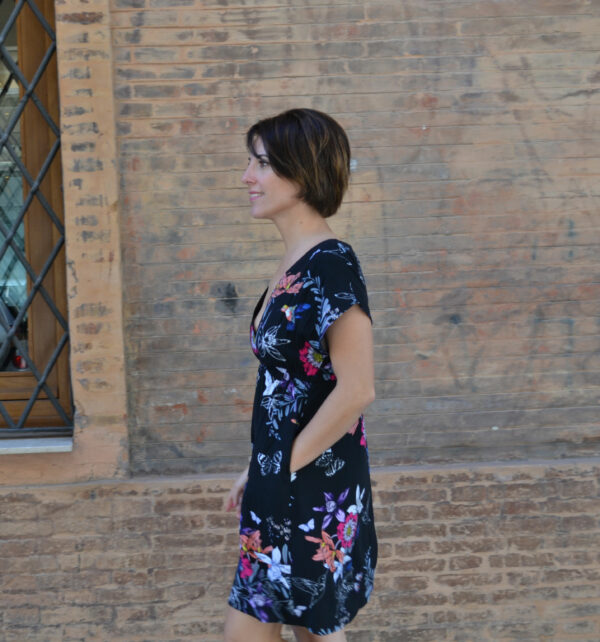 mujer en vestido estampado caminando delante de un muro