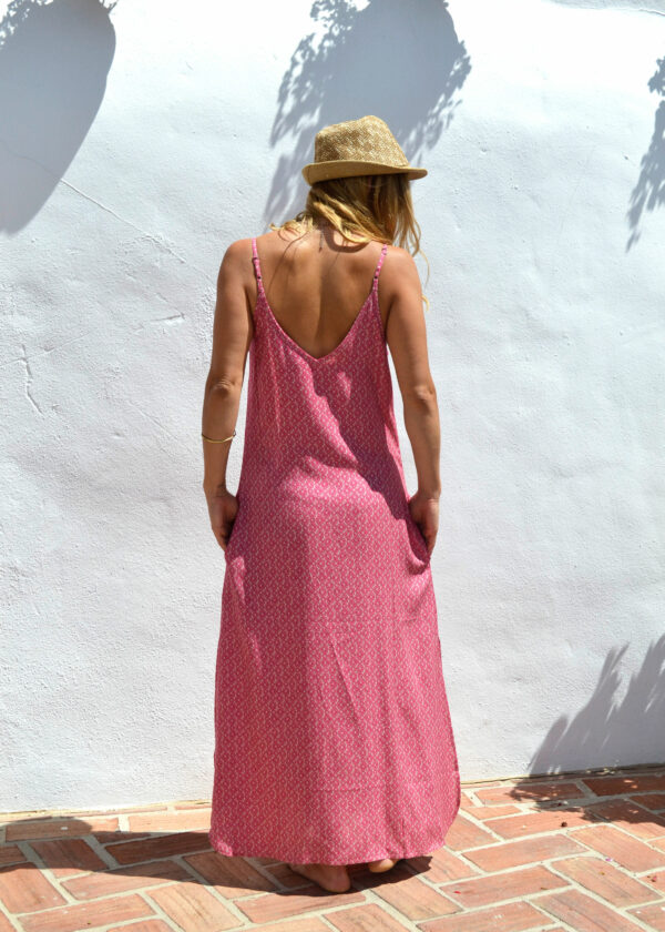 mujer en un hermoso vestido estampado largo de espaldas a la pared y sombrero