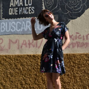 mujer en vestido estampado delante de un muro sonriendo